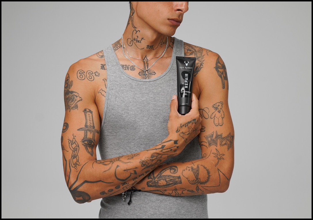 Tattooed model holding a Mad Rabbit tube